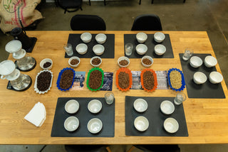 Table with coffee bean samples and tasting cups on a wooden surface