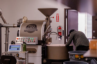 Mill City Roaster coffee roasting machine with employee checking the beans in the roastery room.
