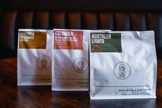 Three coffee bags from Ethiopia, Colombia, and Northern Lights on a wooden surface with a dark background.